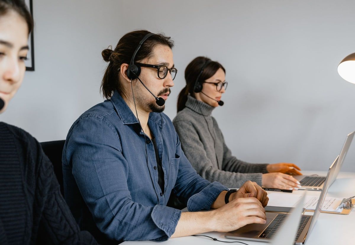 Natural-colour photograph of a customer service team wearing headsets and working at laptops