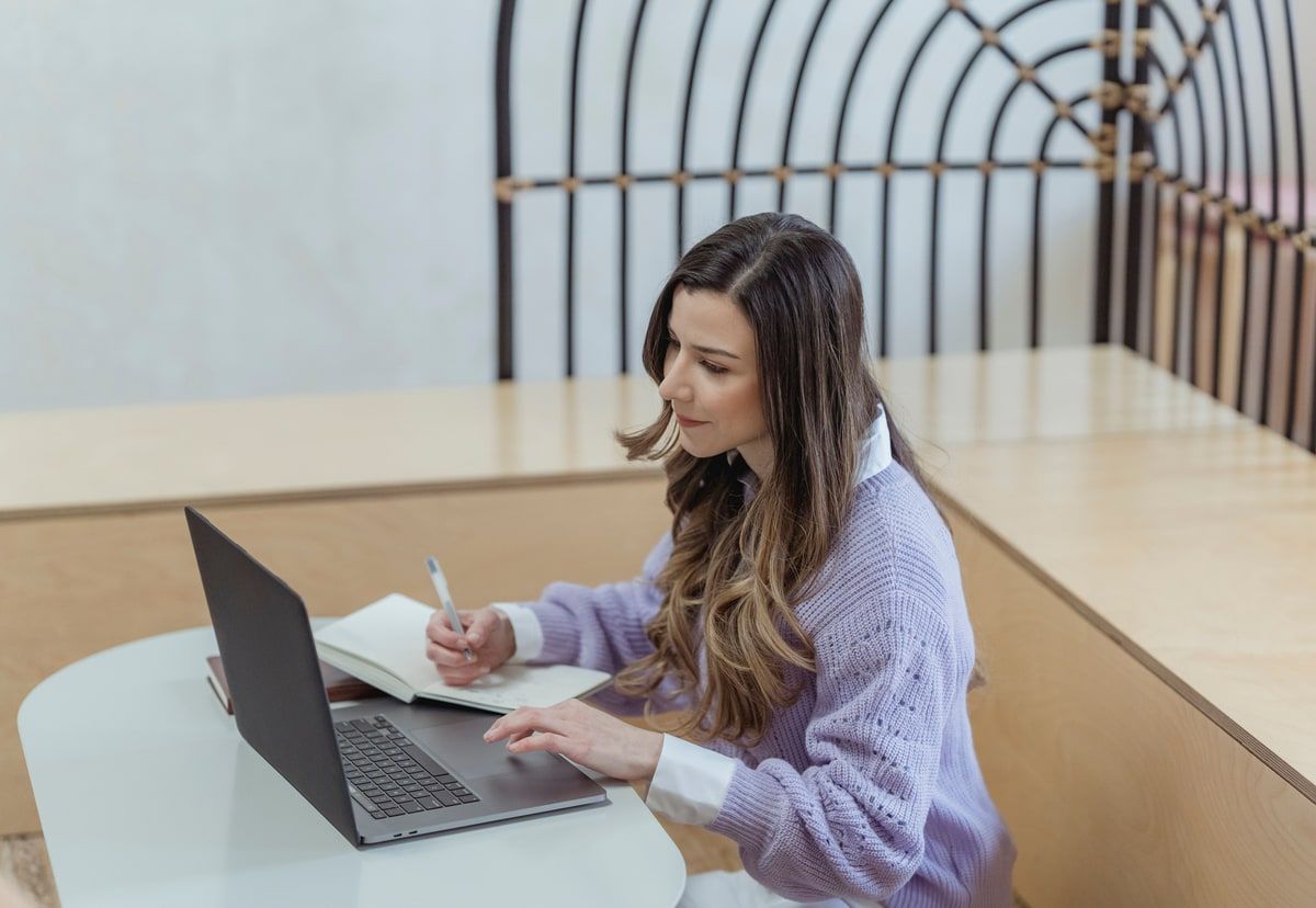 A product designer writing interface notes beside an open laptop