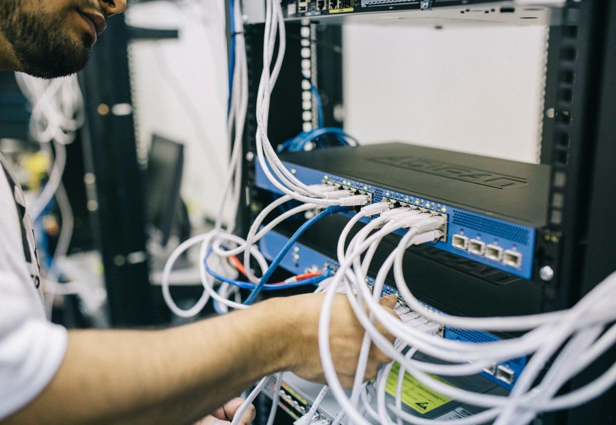 An engineer tracing network cables connected to equipment in a server rack.