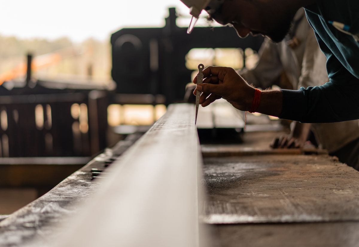 A carpenter carefully measuring material in a workshop, representing the planning and precision involved in bespoke software