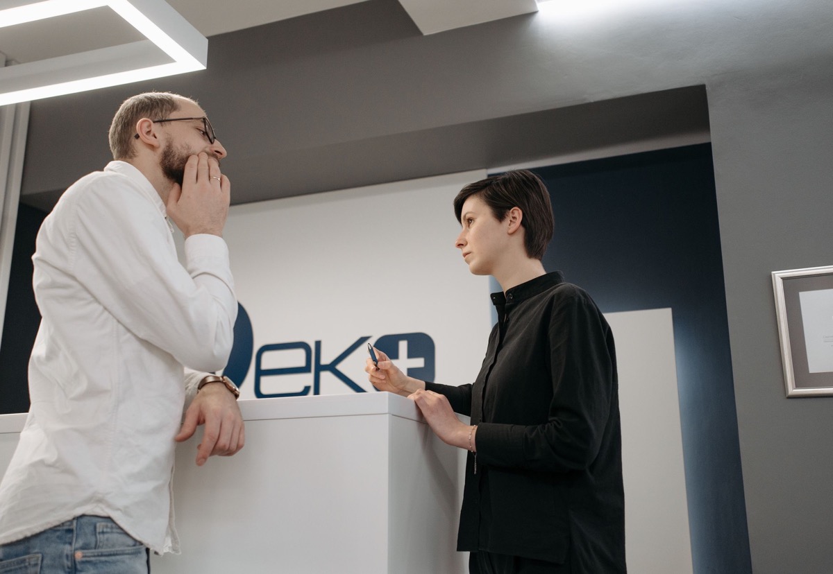 A customer and member of staff discussing a request across a modern reception counter
