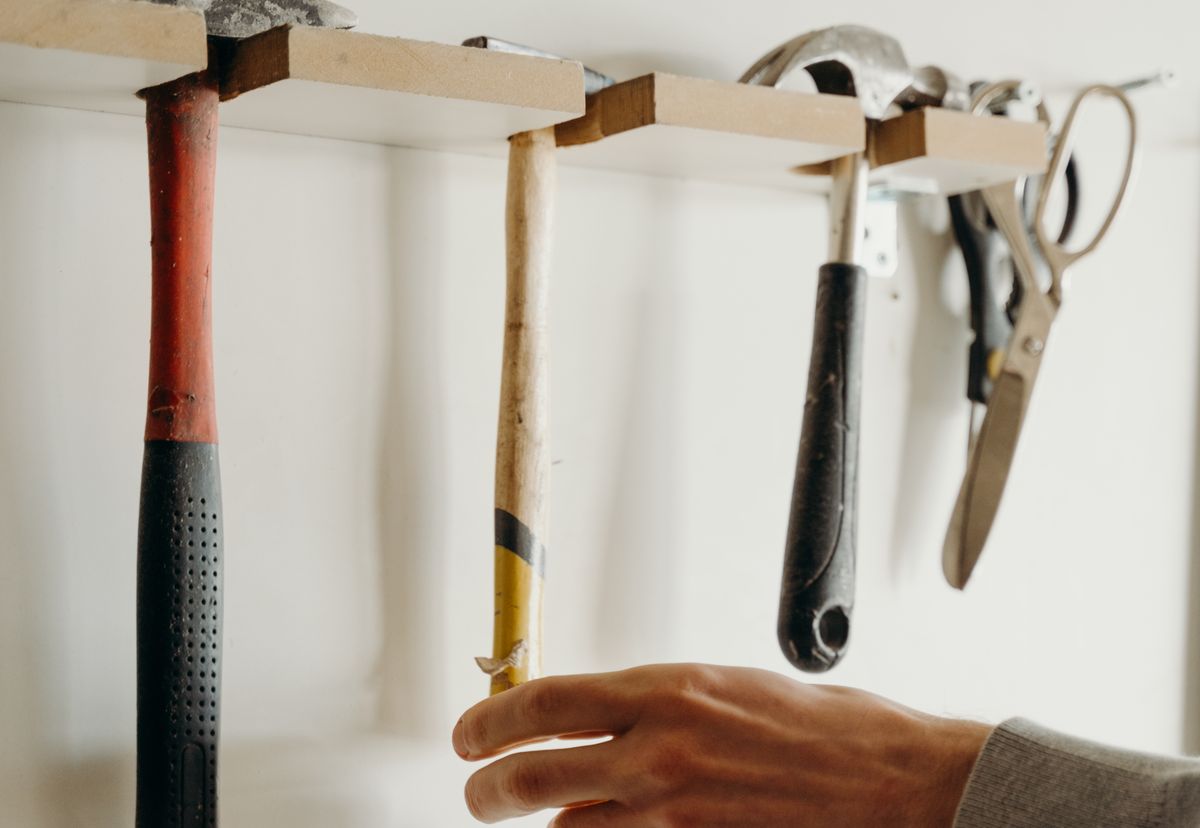 A hand choosing from several workshop tools, representing the need to match an AI coding tool to the development task