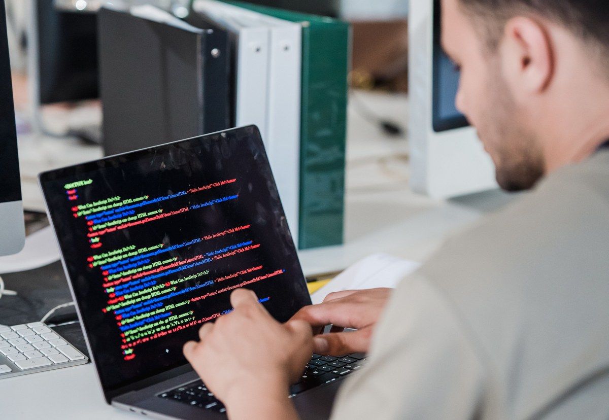 A software developer studies code on a laptop at a desk in a modern office