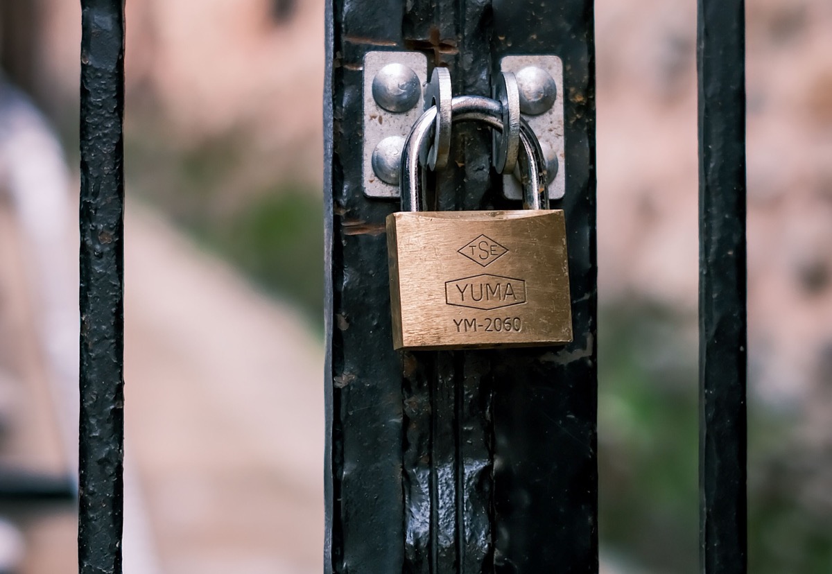 A padlock securing a black metal gate, representing layered protection in front of a web application