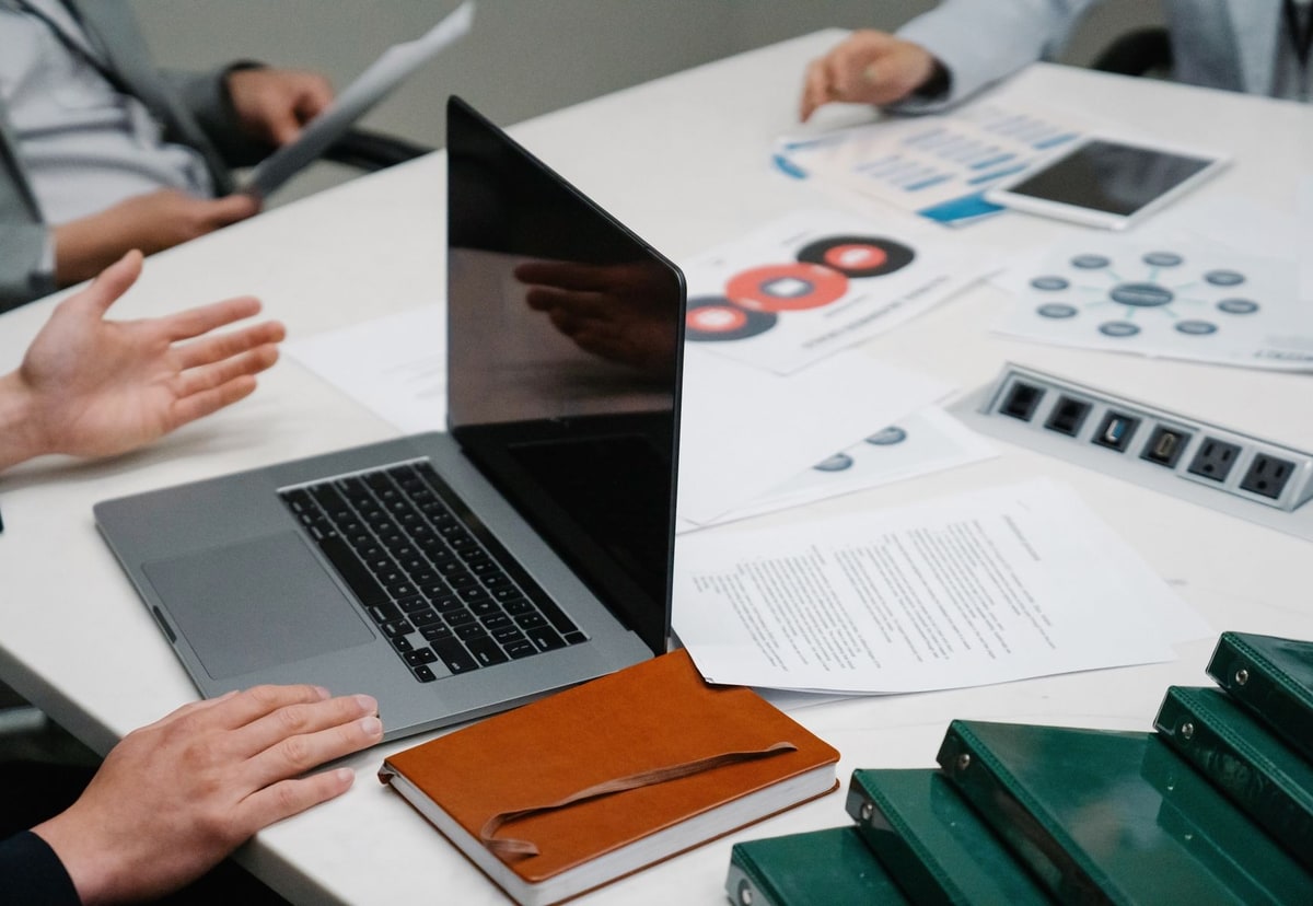 A business meeting table with a laptop, documents and folders representing company data moving into a working process