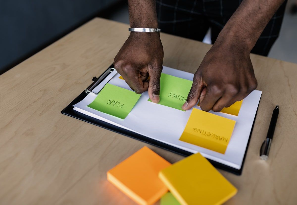 Hands arranging planning notes on a clipboard during a software project workshop.