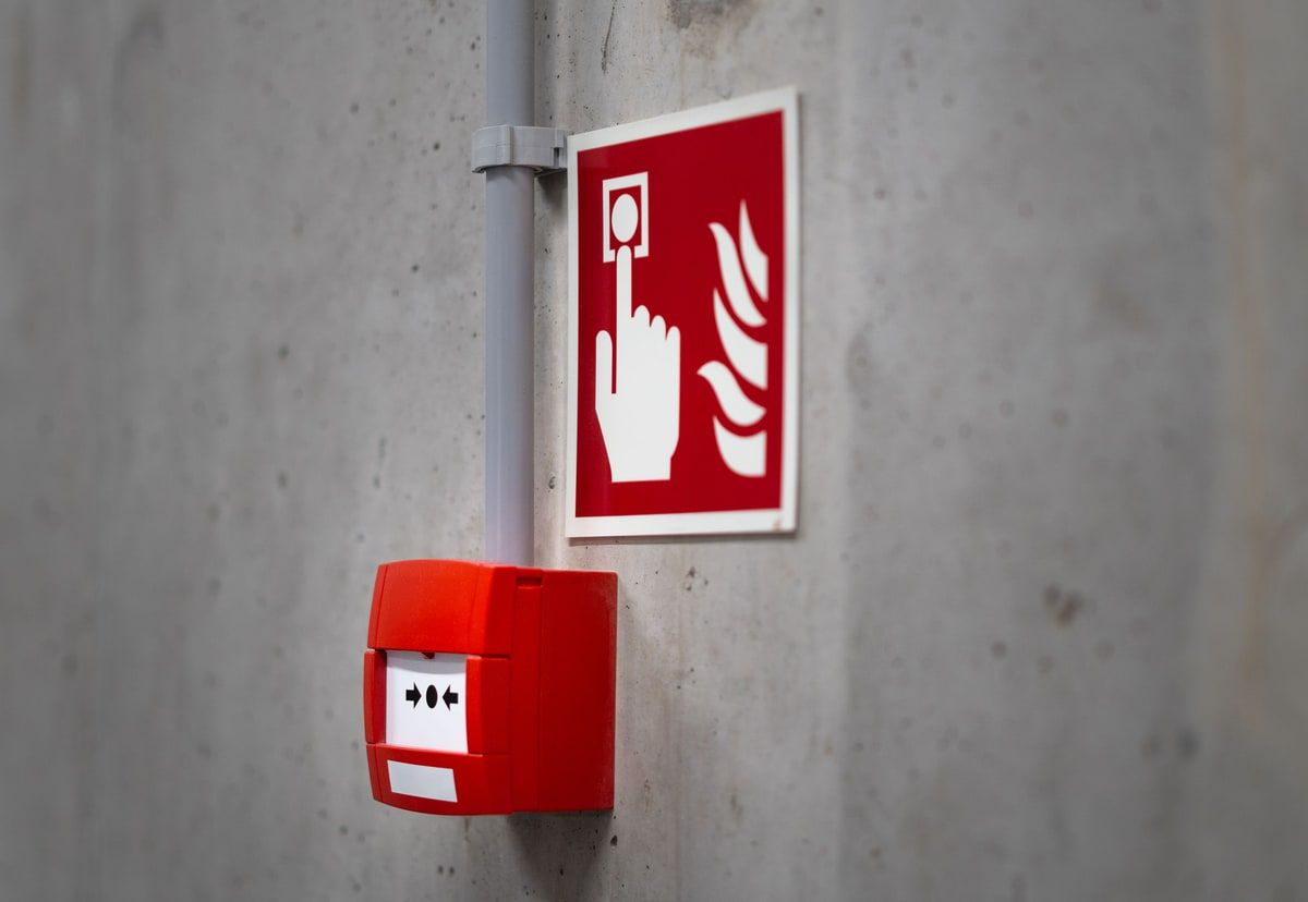 A red emergency alarm button mounted on a concrete wall