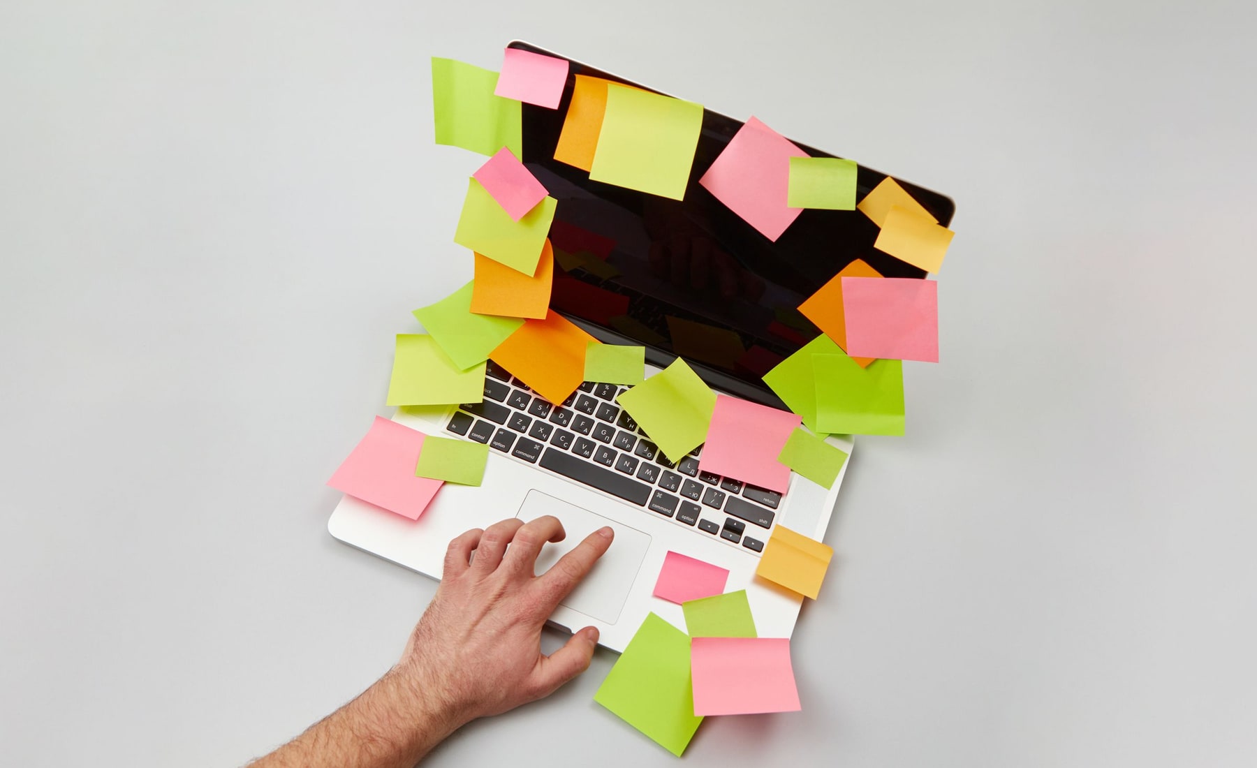 A hand using a laptop surrounded by colourful notes during interface planning