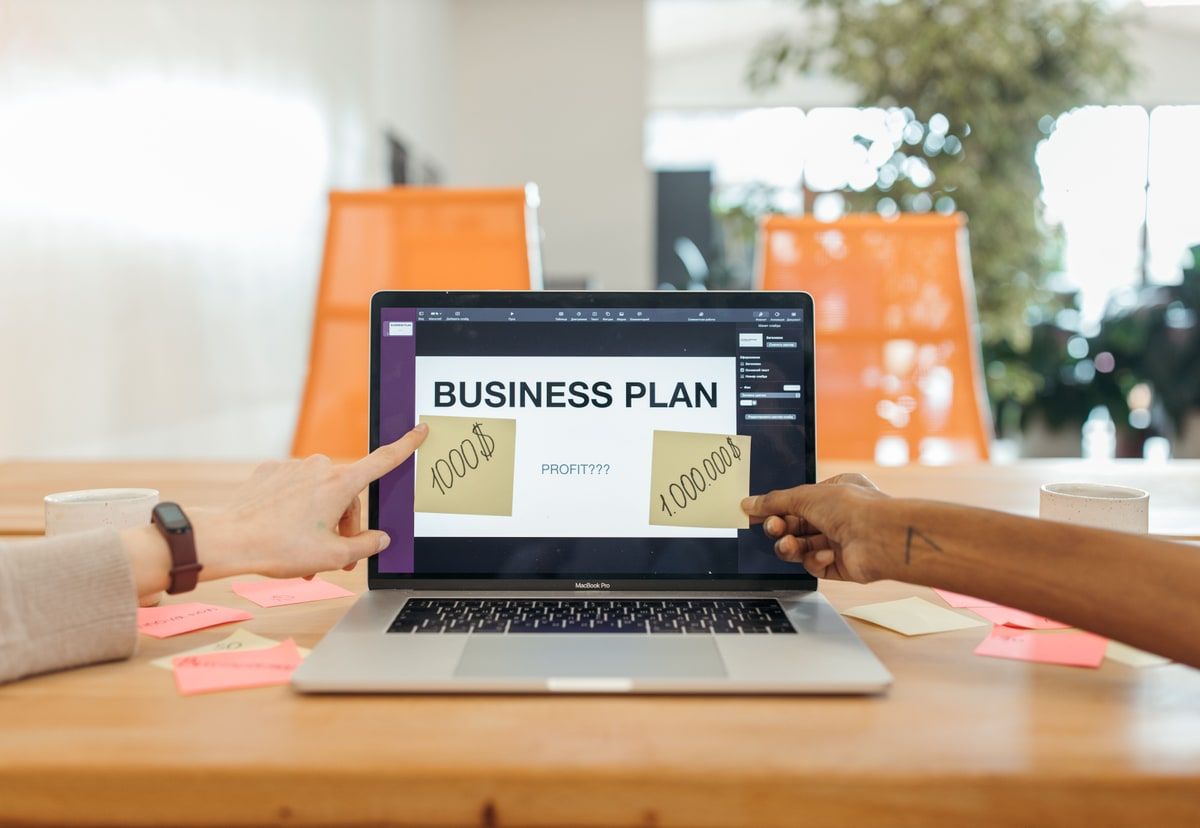 Two colleagues reviewing a business plan on a laptop surrounded by planning notes