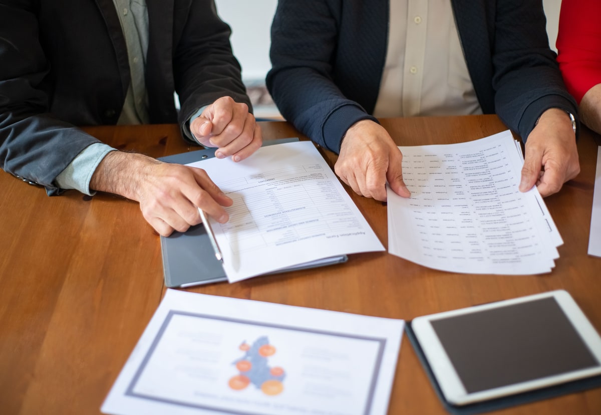 Two professionals pointing at printed proposal documents during a review meeting