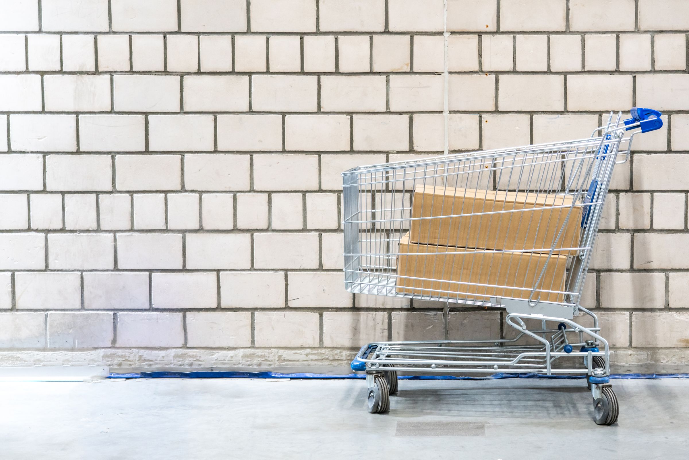 Metal shopping trolley carrying plain cardboard boxes, representing accumulated technical debt adding weight to future software changes