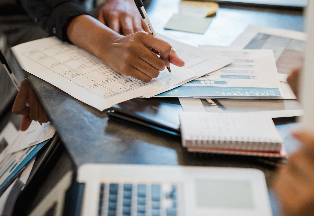 A business professional reviewing printed content plans and making notes at a shared desk