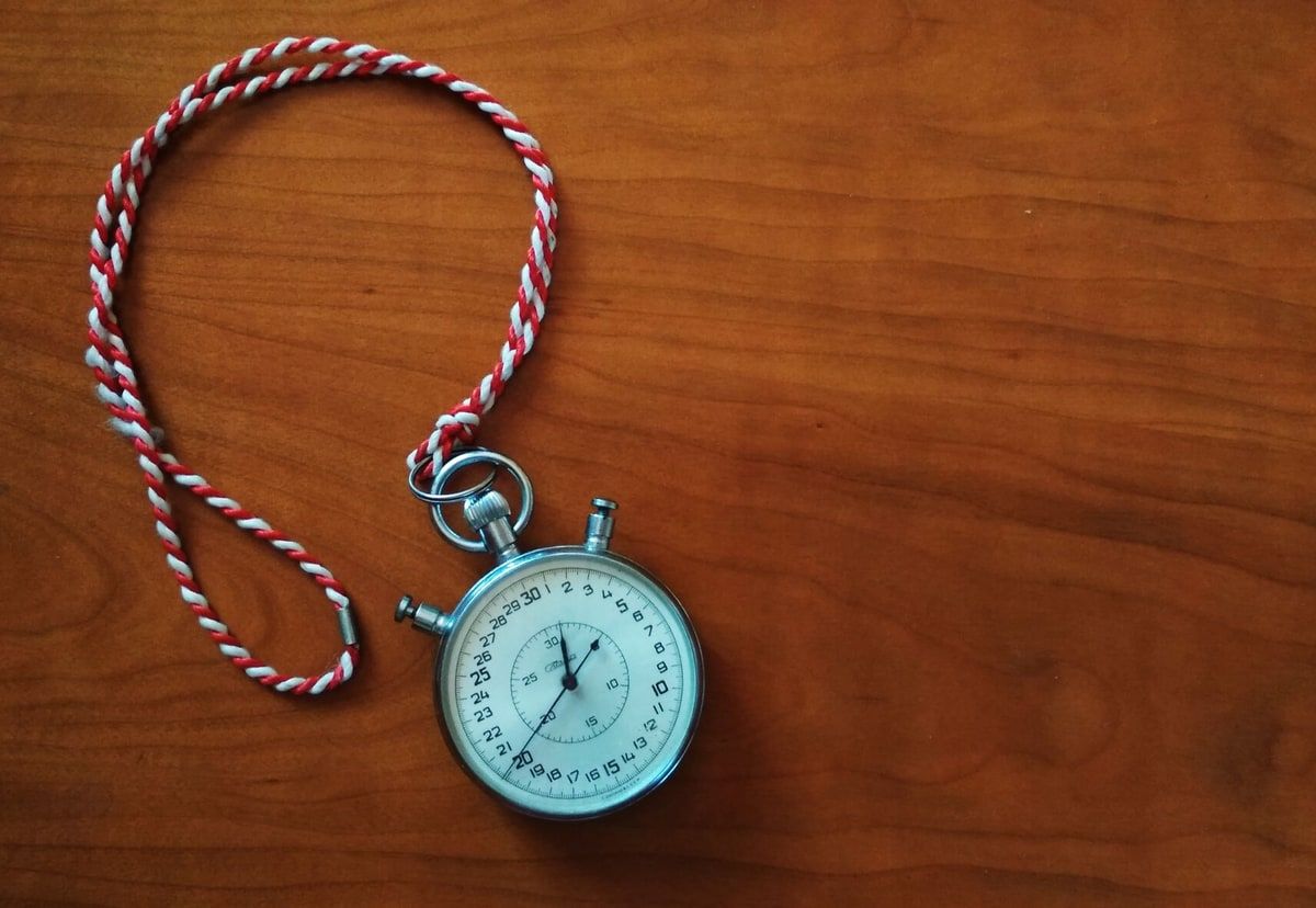 A silver mechanical stopwatch resting on a wooden surface, representing careful Laravel code measurement