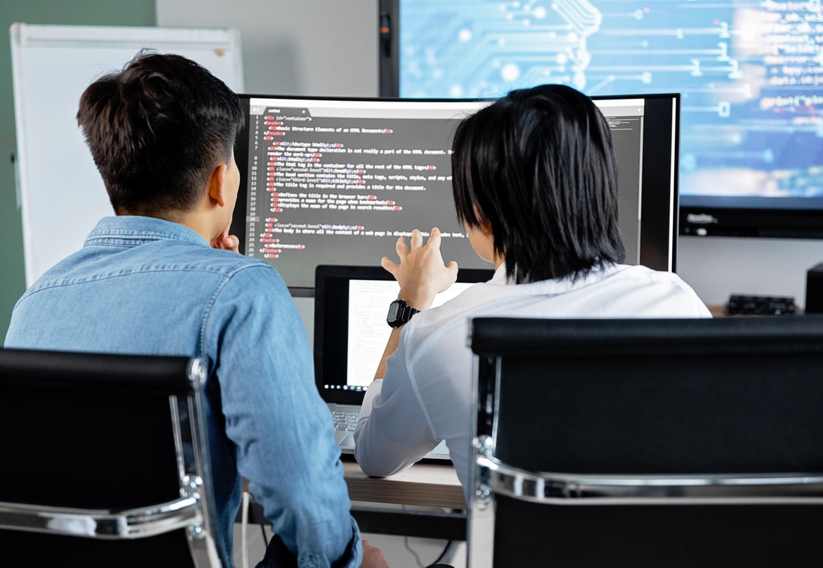Two software developers discussing code together at one workstation