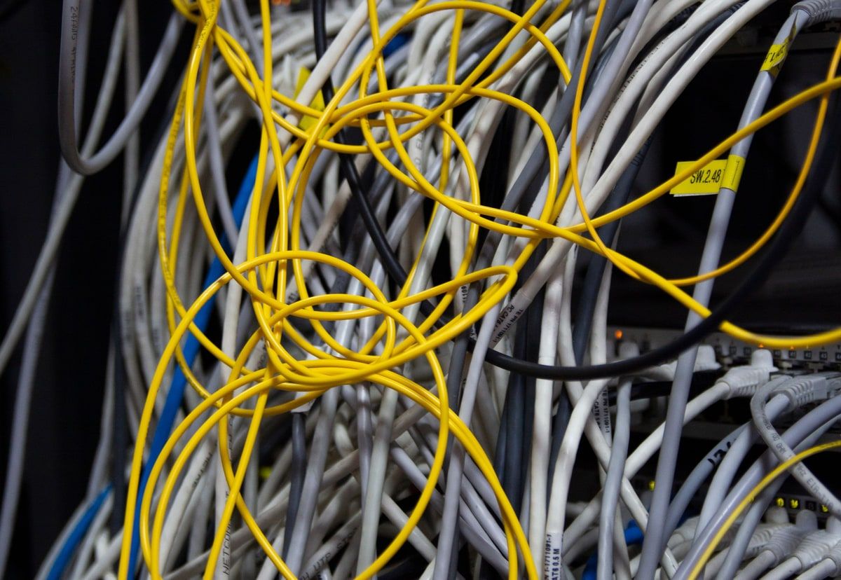 A close view of tangled network cables inside a server rack, representing the uncertainty around an inherited legacy application
