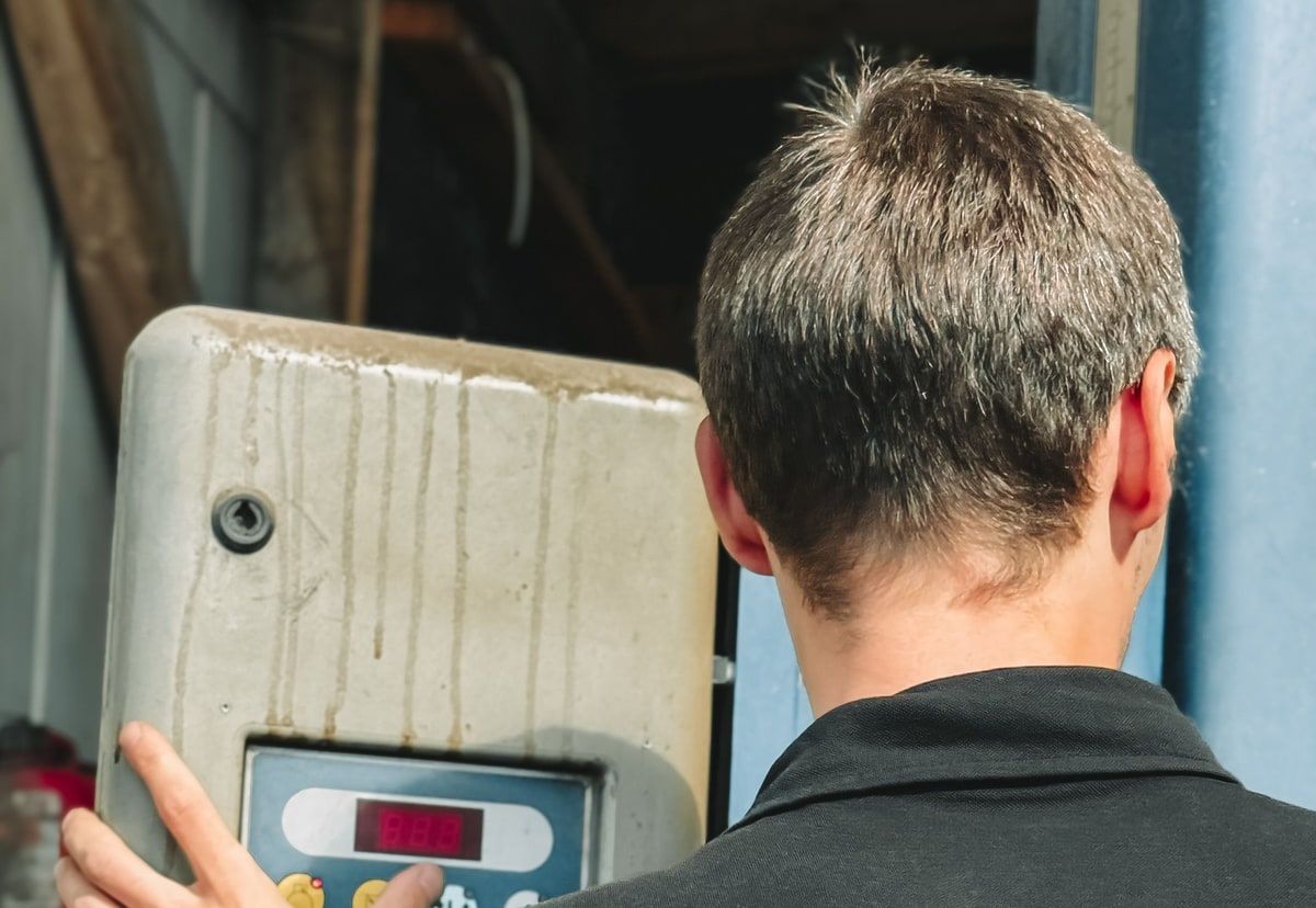 A technician inspecting the controls of an older industrial machine in a workshop.