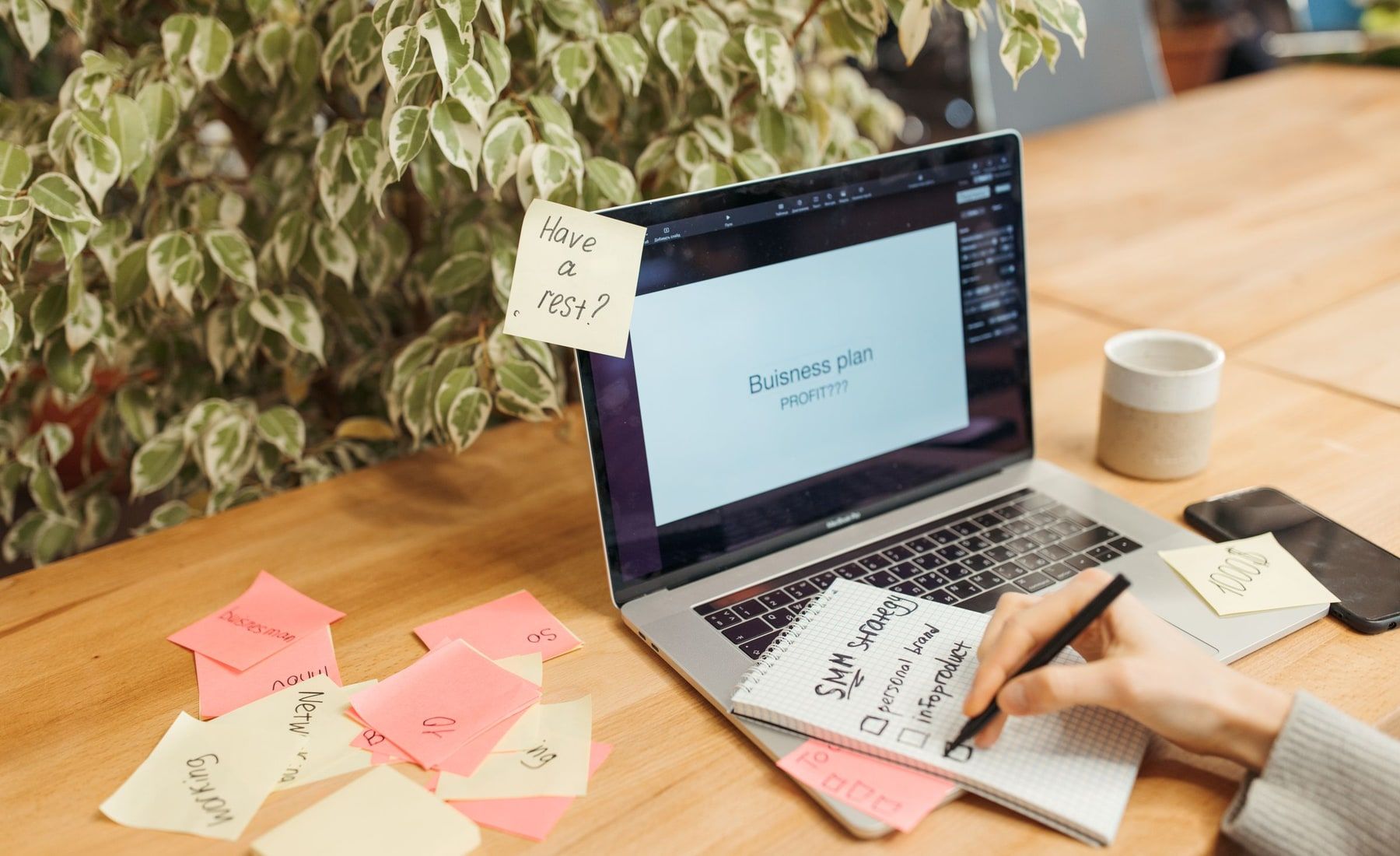 A person planning a focused first product release with a laptop, notebook and sticky notes