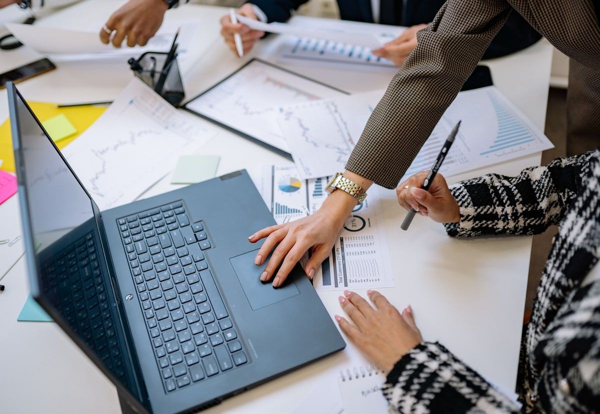 Business team comparing charts and information around a laptop during a software decision meeting