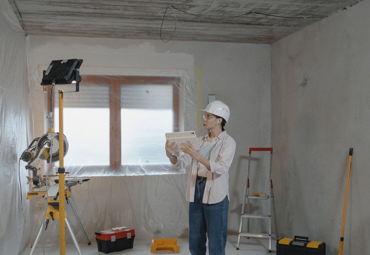 Site manager wearing a hard hat and holding a tablet while inspecting a residential renovation