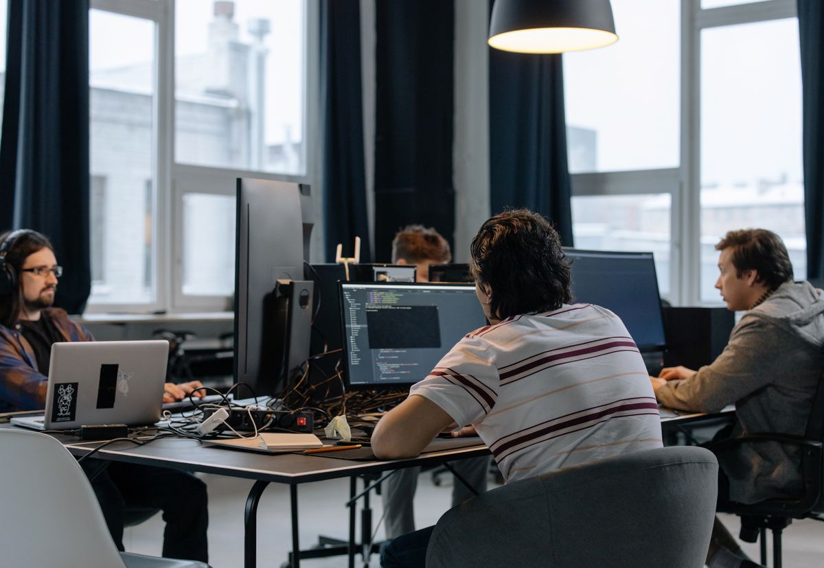 A software development team working at computers in a shared office, representing the planning and ongoing operation behind a SaaS application