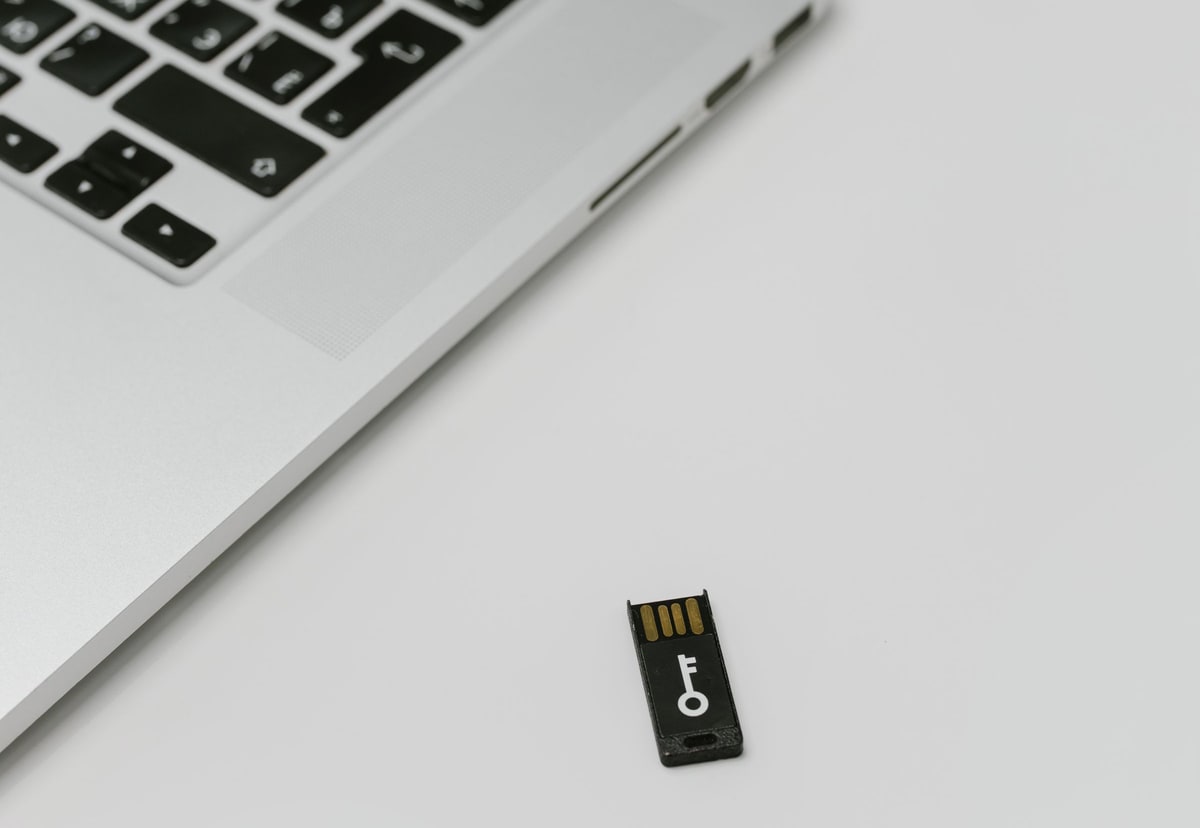 A small USB security key resting beside the keyboard of a silver laptop