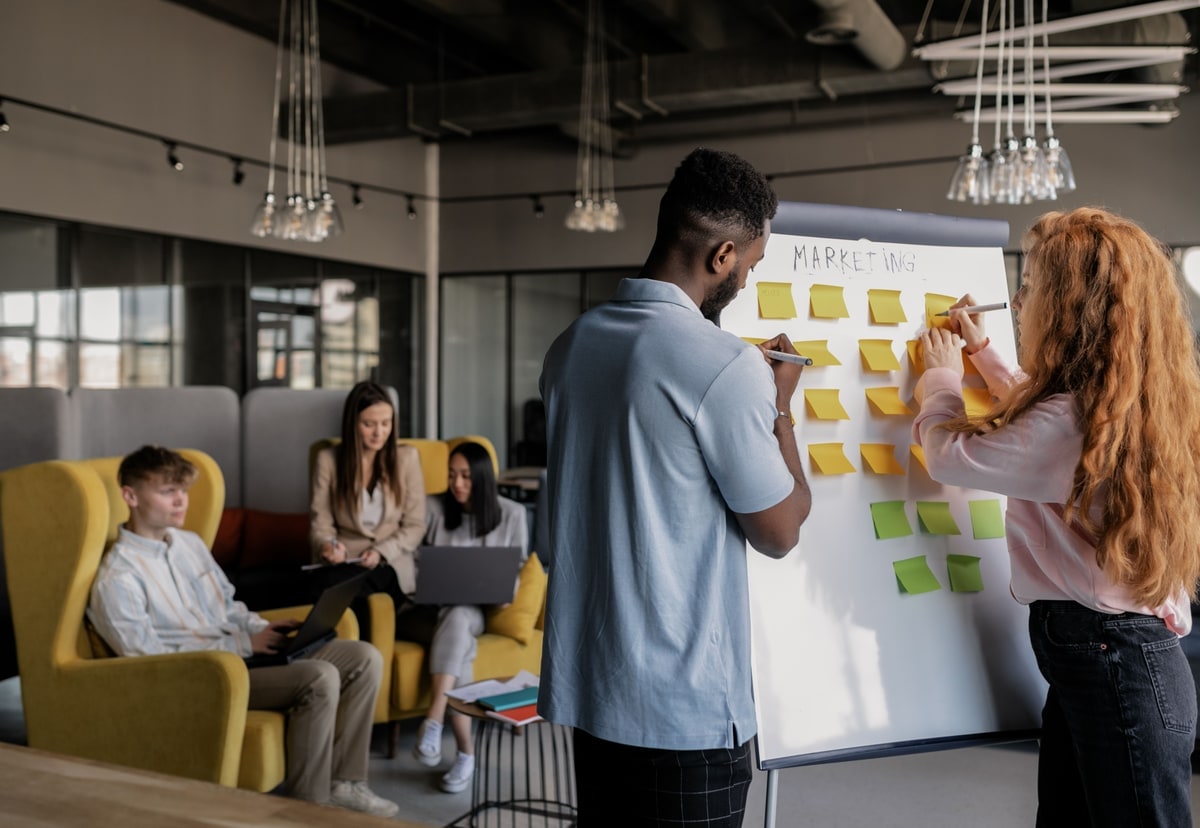 Two colleagues developing ideas together on a whiteboard covered with sticky notes