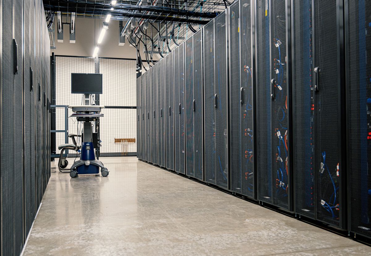 A corridor of server racks in a modern data centre, representing the infrastructure behind different types of web hosting