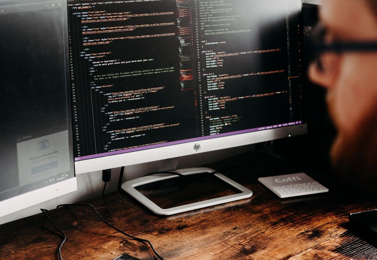 A developer working at a desk with a code editor open across two monitors