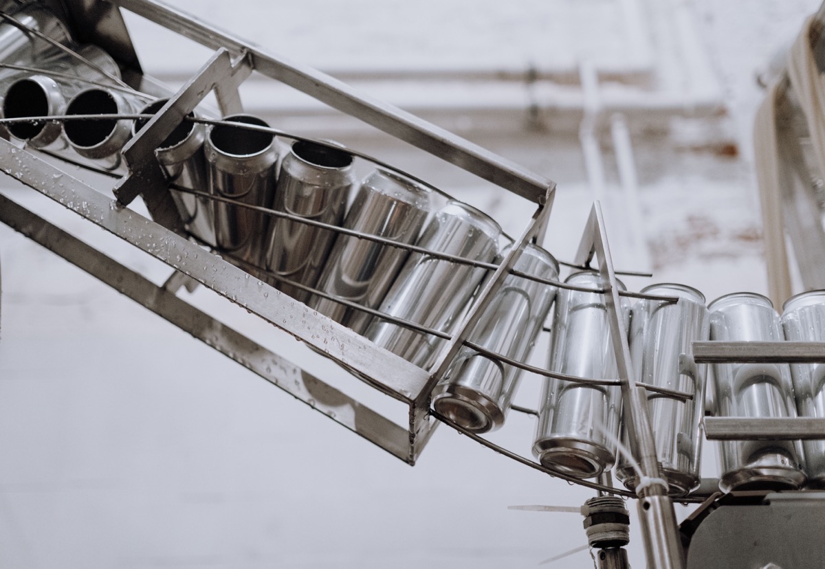 Aluminium cans moving through an automated production line, representing repeatable GitHub Actions checks and deployment steps