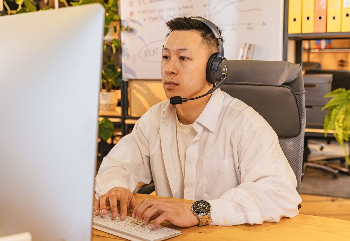 Customer support worker wearing a headset while using a computer in a modern office