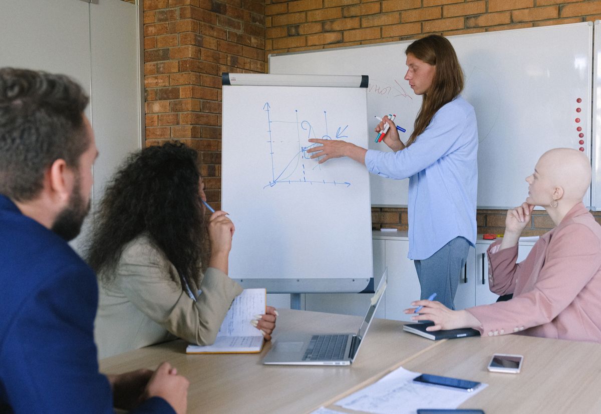 A consultant explaining a process on a flipchart to colleagues during a business workshop