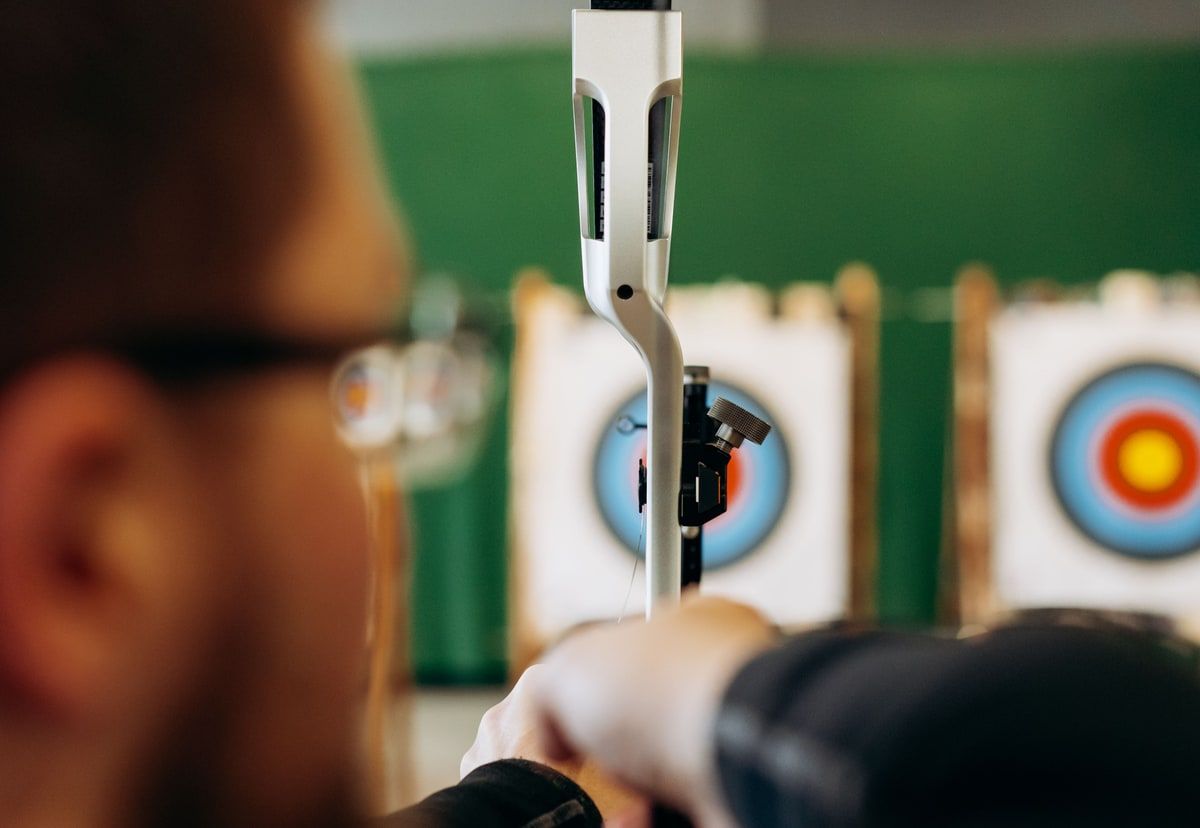 An archer lines up a shot towards a clearly visible target at an indoor range