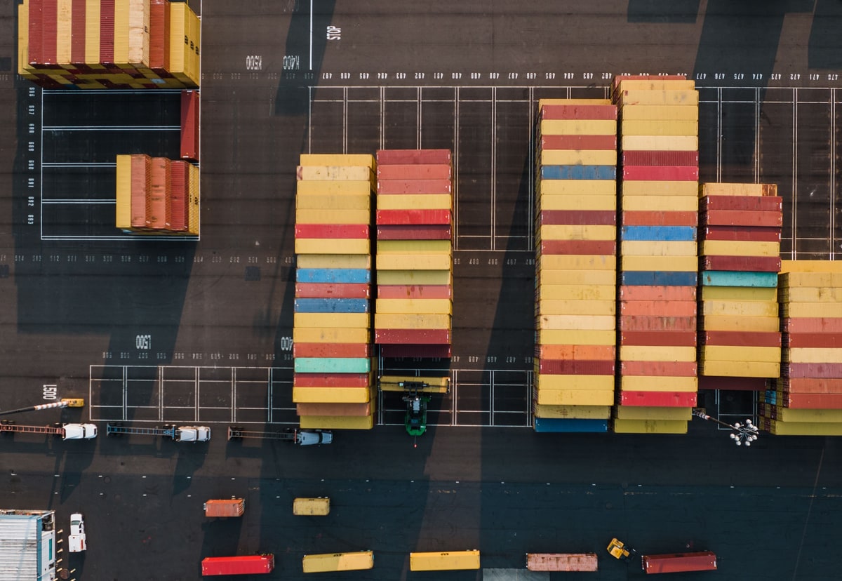 Rows of freight containers organised at a port, representing consistent Docker application packages
