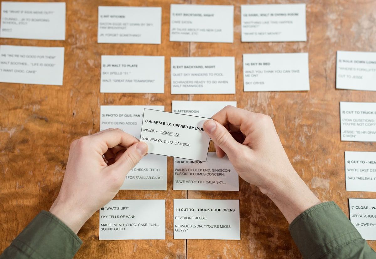 Hands arranging story planning cards across a wooden desk