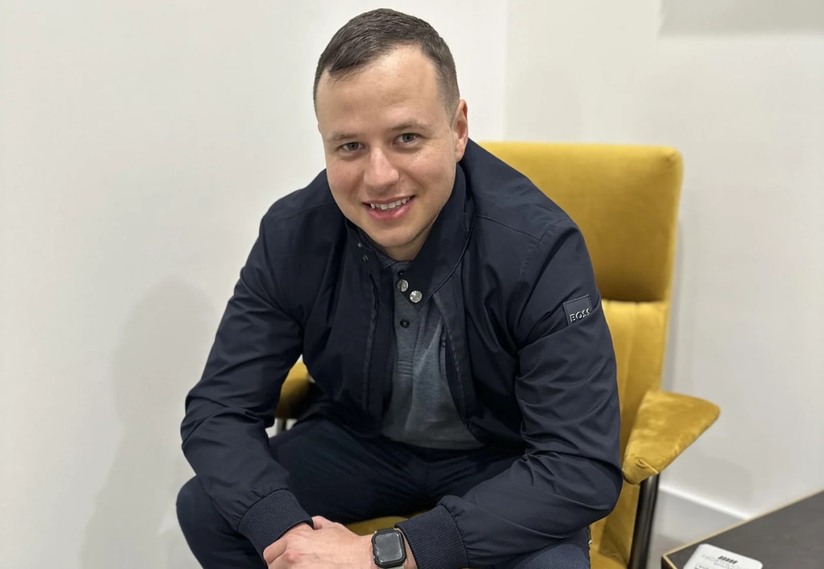 Daniel Mills seated in a yellow chair, photographed in natural colour