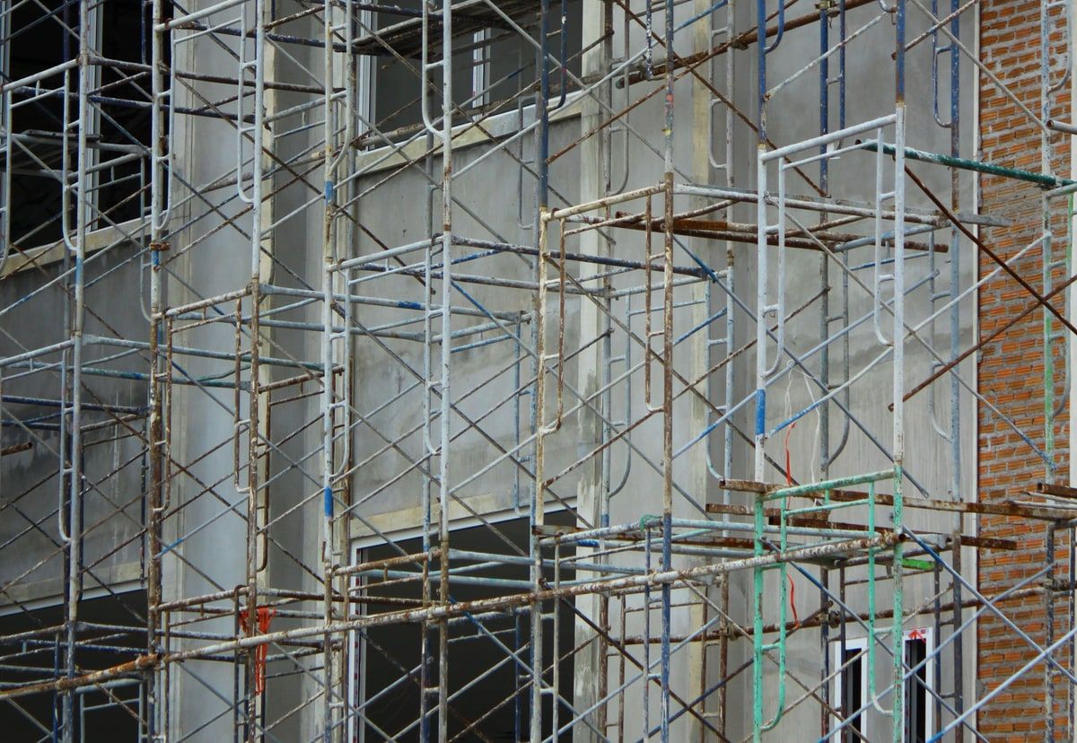 Natural-colour metal scaffolding surrounding a building under construction, representing the shared structure provided by a PHP framework